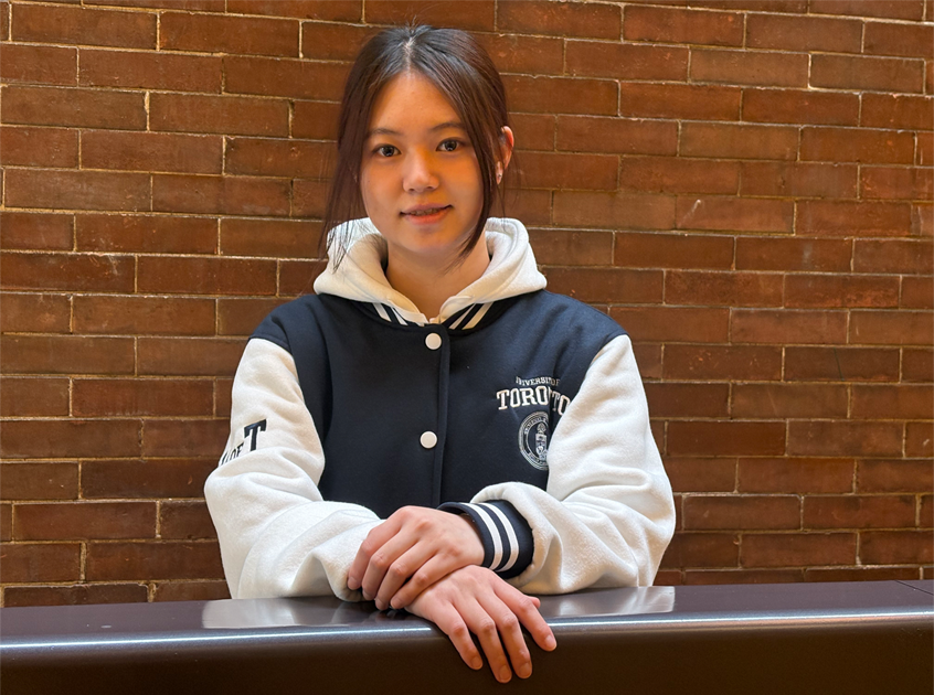 Headshot of Ze (Catherine) Wang standing in front of a brick wall, wearing a u of t jacket.