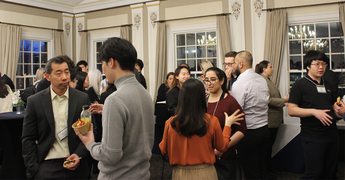 New College Mentorship Reception February 21. Overview shot of various mentors and mentees conversing with each other.